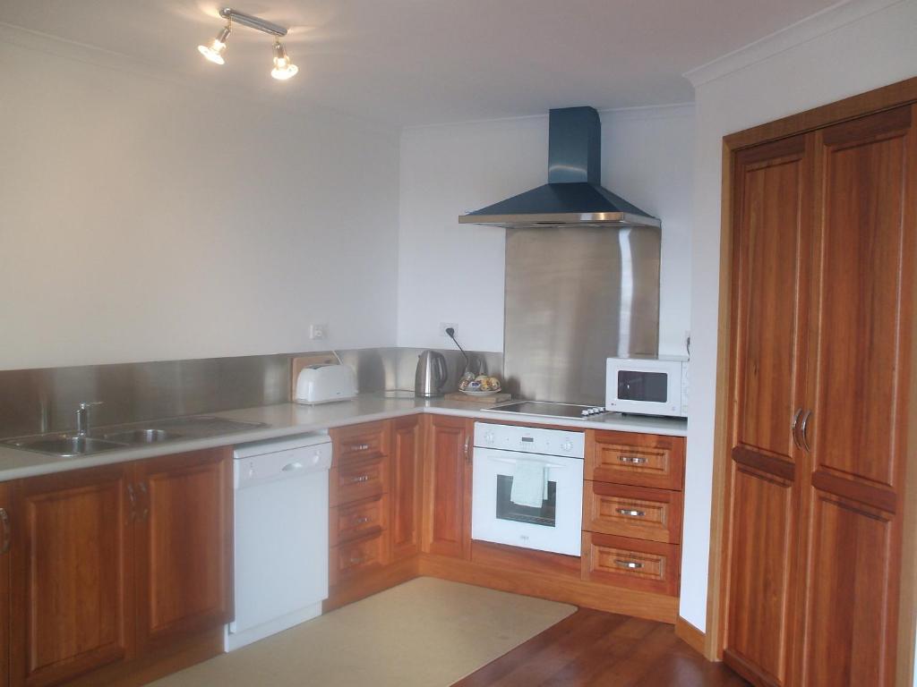 a kitchen with wooden cabinets and a white stove top oven at St Helens On The Bay in St Helens