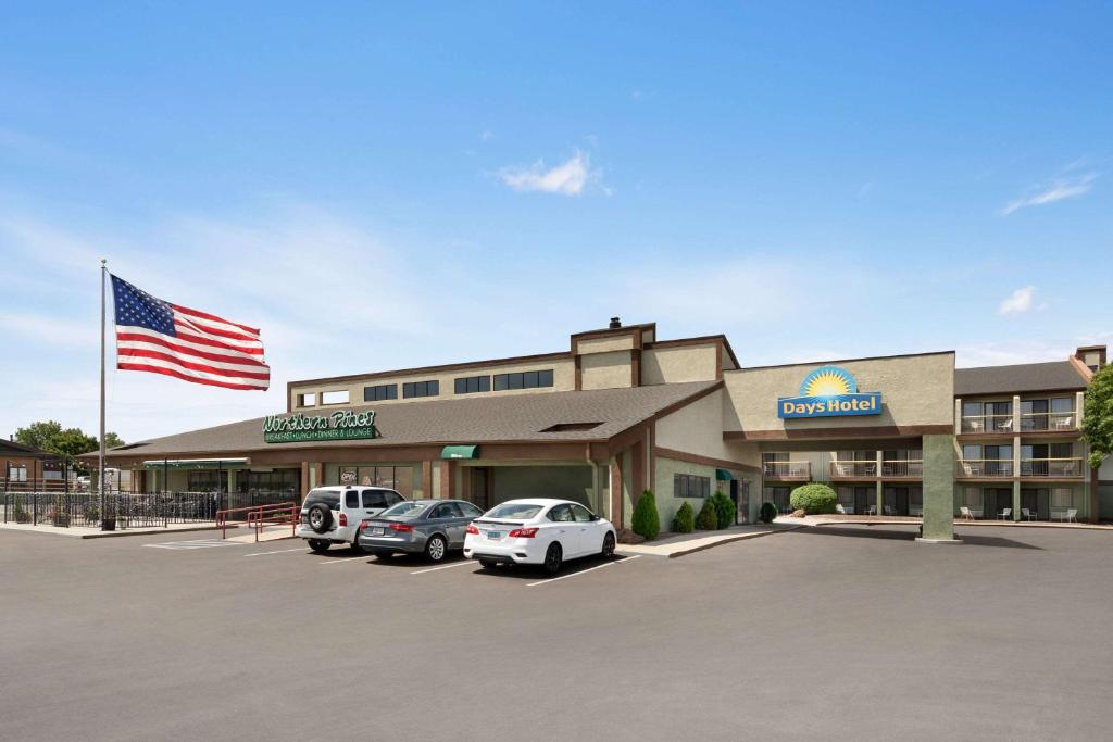 a hotel with cars parked in a parking lot with an american flag at Days Hotel by Wyndham Flagstaff in Flagstaff