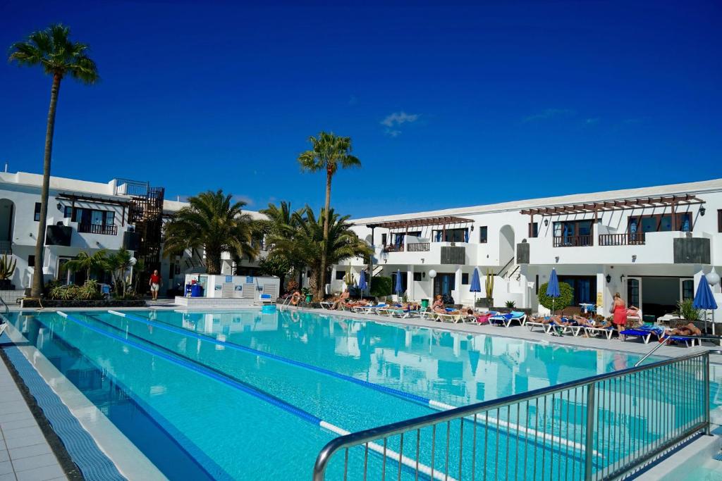 una grande piscina con palme e edifici di Plaza Azul a Puerto del Carmen