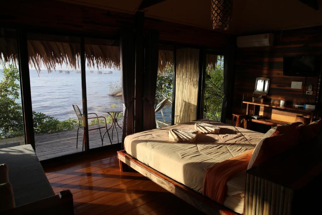 1 dormitorio con cama y vistas al agua en wetlandcamp บ้านชายเล, en Phatthalung