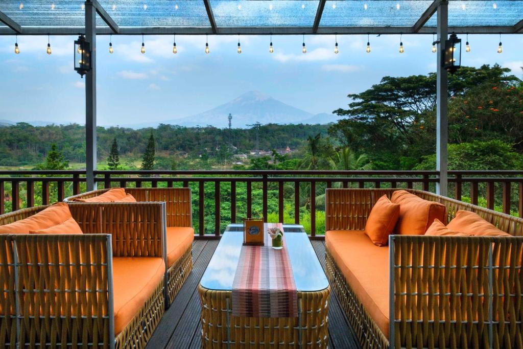 a patio with two chairs and a table on a deck at Puri Asri Hotel & Resort in Magelang