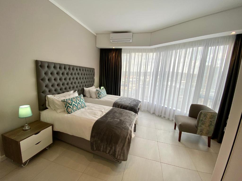 a bedroom with a bed and a chair and a window at Menlyn Maine Residence 11th Floor Apartment in Pretoria