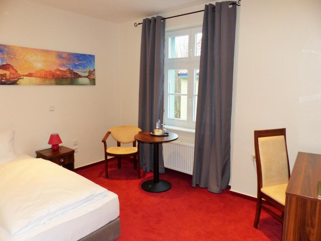 a bedroom with a bed and a table and a window at Hotel &amp; Restaurant ,,Zur Alten Oder&quot; in Frankfurt-Oder in Frankfurt Oder