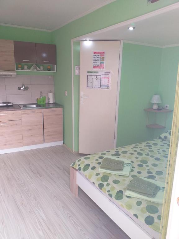 a room with a bed and a kitchen with a refrigerator at Apartman Andjela 1 in Vrdnik