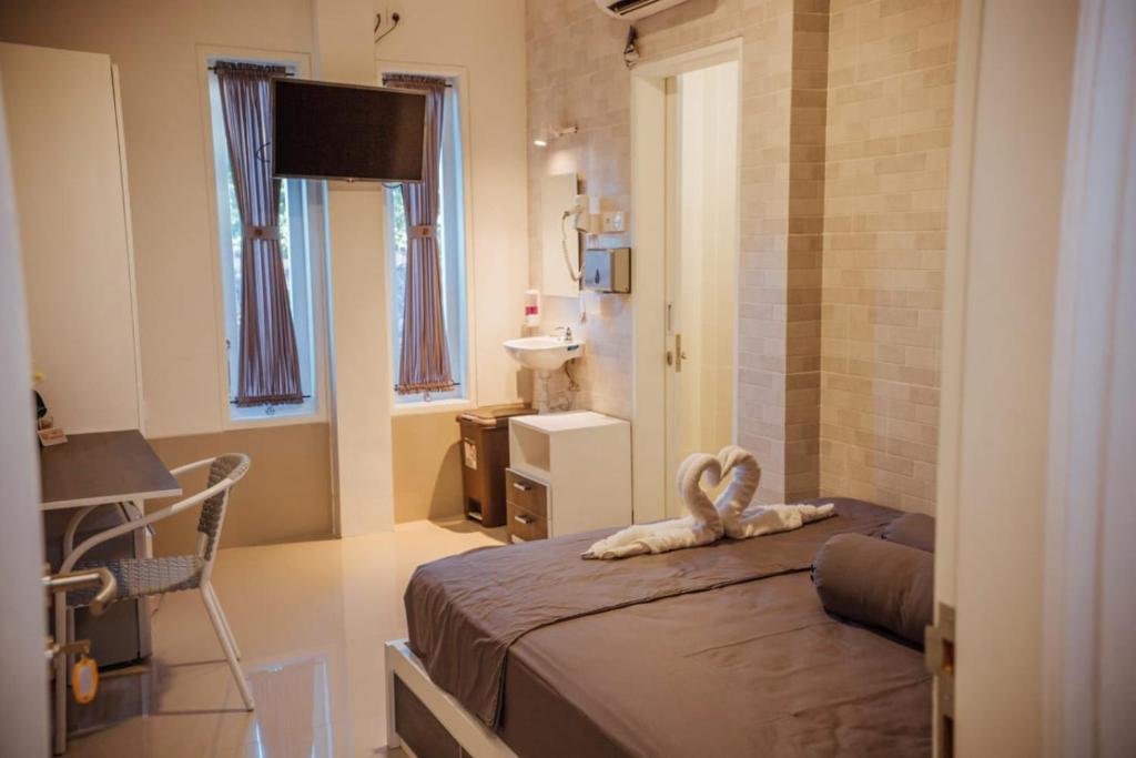 um quarto com uma cama, uma mesa e um lavatório em Simple Kuta Bedroom em Denpasar
