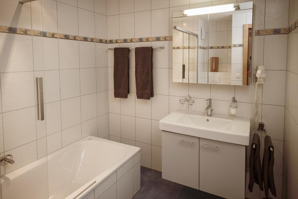 a white bathroom with a tub and a sink at Haus Mischabel in Zermatt