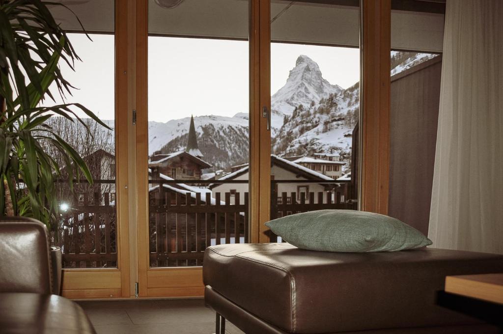 a room with a couch and a window with a mountain view at Haus Mischabel in Zermatt