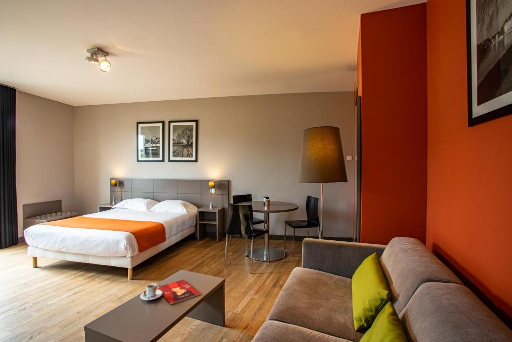 Habitación de hotel con cama y sofá en Adonis Lyon Dock Ouest, en Lyon