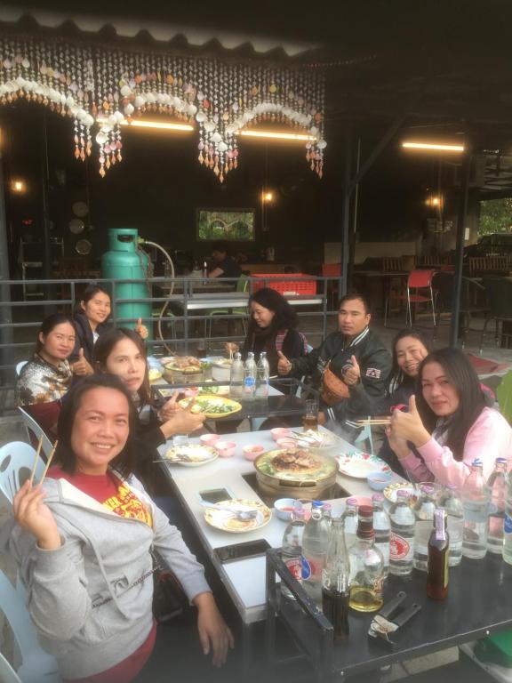 Un gruppo di persone seduti intorno a un tavolo che mangiano di Baan Suan Resort2345 a Ban Nong Waeng