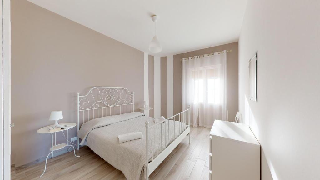 a white bedroom with a bed and a table at Case Playa in Balestrate