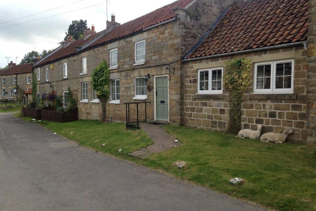 dos ovejas tumbadas en el césped fuera de una casa de ladrillo en SUNNYSIDE COTTAGE HUTTON LE HOLE NORTHYORKSHIRe, en Hutton le Hole