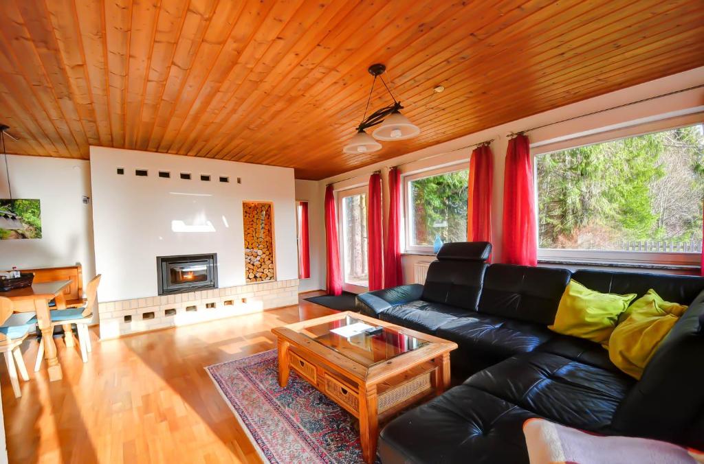 sala de estar con sofá de cuero negro y mesa en Ferienhaus am Feldberg, en Feldberg