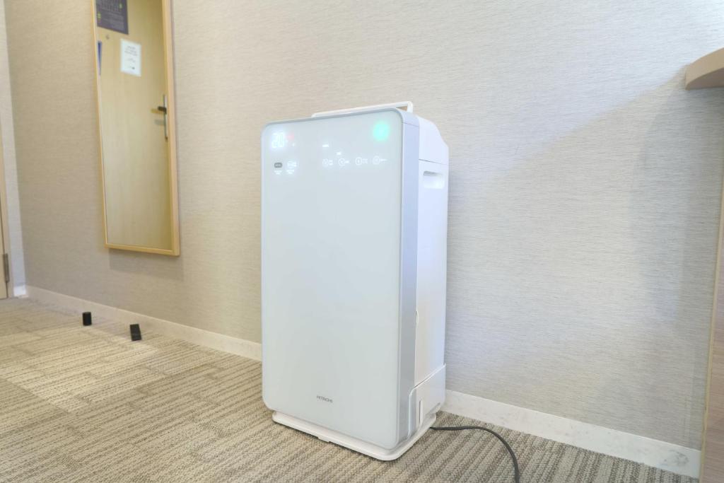 a white refrigerator in the corner of a room at Meitetsu Inn Hamamatsucho in Tokyo