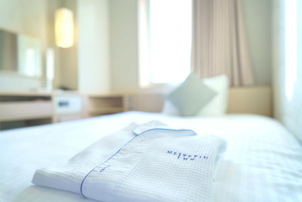 a white towel on a bed in a hotel room at Meitetsu Inn Hamamatsucho in Tokyo