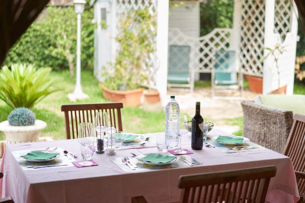 una mesa con mantel blanco y una botella de vino en Villa in Athena Resort en Scoglitti