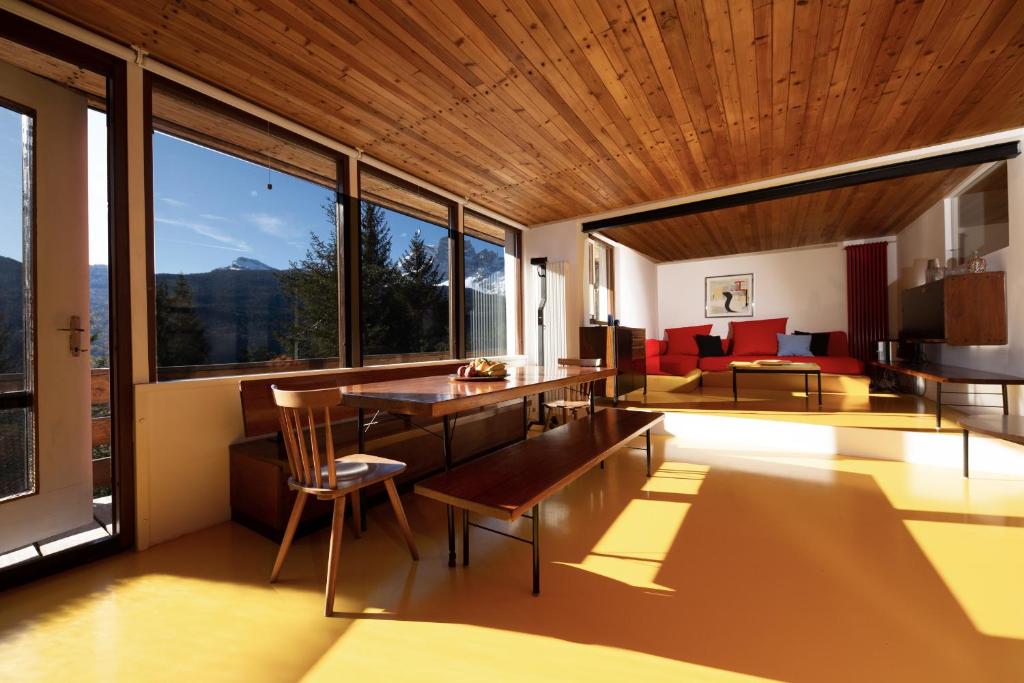 ボルカ・ディ・カドーレにあるChalet Dolomiti 430のリビングルーム(テーブル、椅子、大きな窓付)