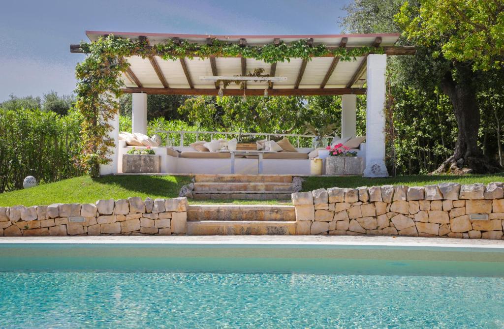 pergola obok basenu z kanapą pod nią w obiekcie TD Dimora di Genna Trulletto with Lush Garden Pool w mieście Castellana Grotte