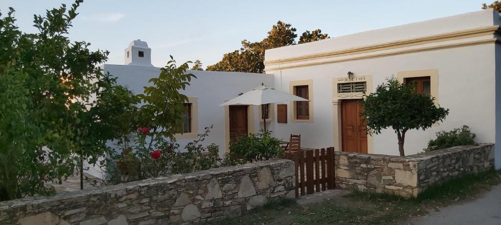 a white house with an umbrella and a stone wall at Traditional house in Asfendiou in Kos Town