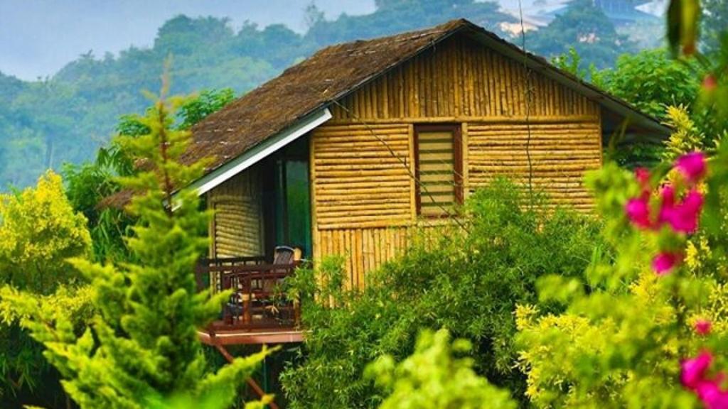 uma pequena casa de madeira com um alpendre numa floresta em KOOMANKOLLY RESORT em Thirunelli