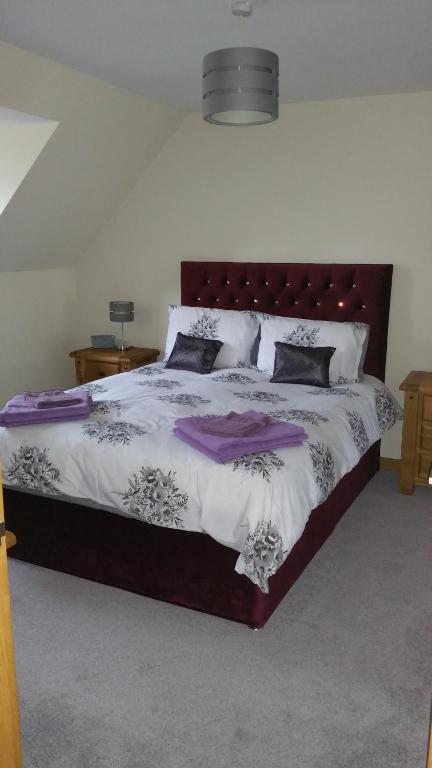 ein Schlafzimmer mit einem großen Bett mit lila und weißen Laken in der Unterkunft The Cobblers in Inverness