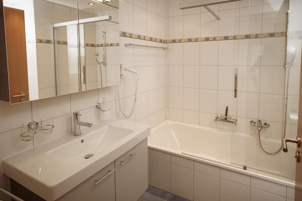 a white bathroom with a tub and a sink at Haus Mischabel in Zermatt