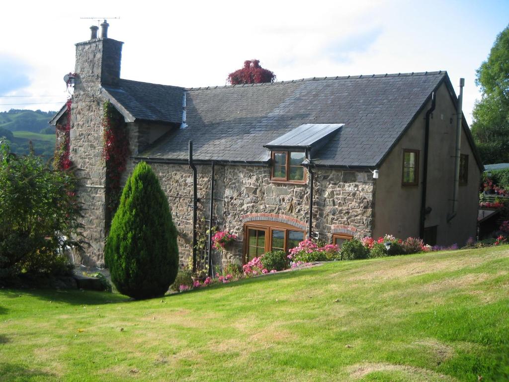 uma casa de pedra com um telhado preto em TAN Y GRAIG em Meifod