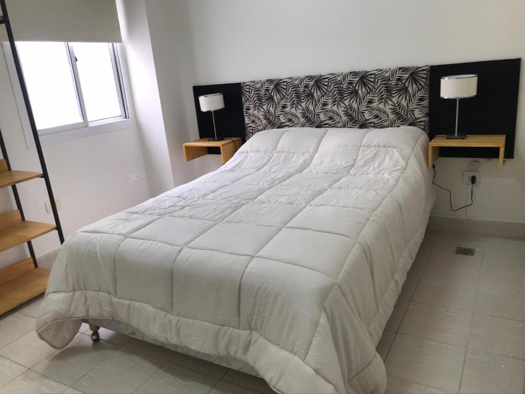 1 cama blanca grande en un dormitorio con 2 lámparas en Luminoso a dos cuadras de la plaza en Salta