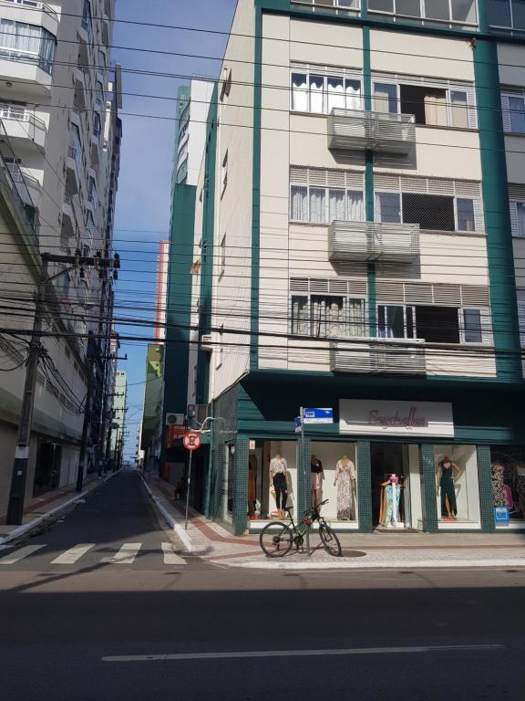 una bicicleta estacionada frente a una tienda en una calle de la ciudad en Edifício Quadra mar, pe na areia a 150 metros saída rua reta ilha, en Balneário Camboriú