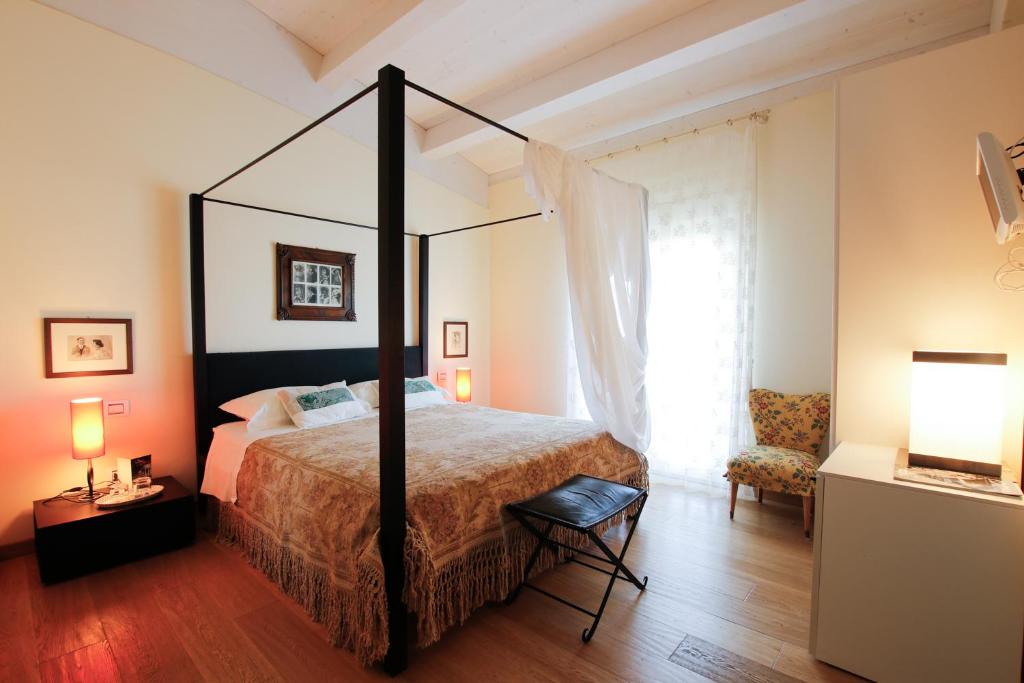 una camera con letto a baldacchino e sedia di B&B Villa FioreConero a Montacuto