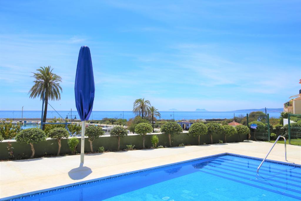 een zwembad met parasol en de oceaan op de achtergrond bij Apartment LORNA in Estepona