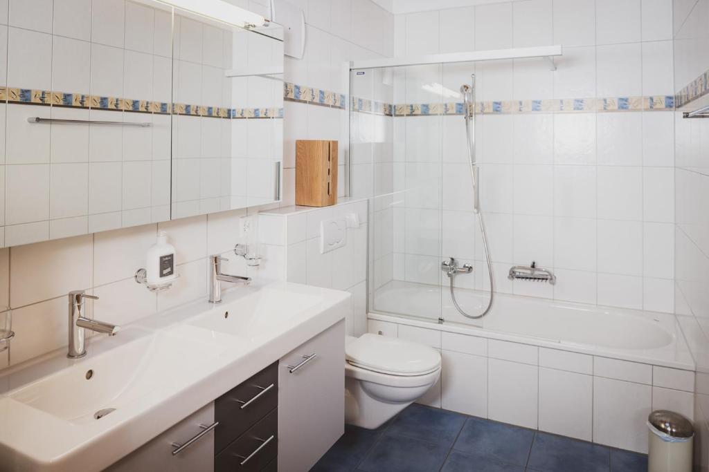 a white bathroom with a toilet and a tub and a sink at Haus Mischabel in Zermatt