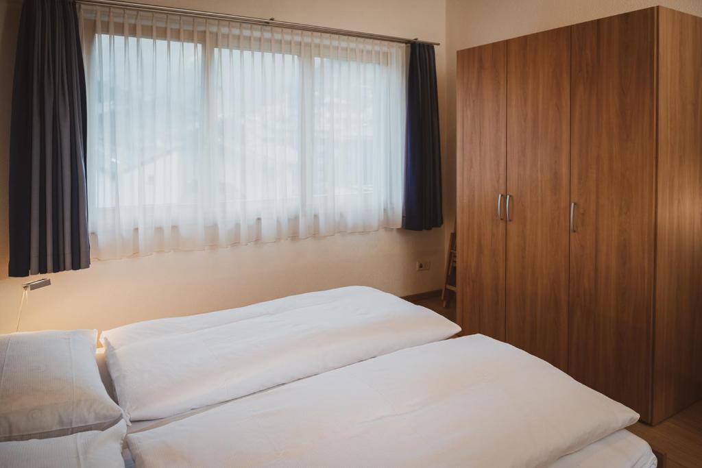 a bedroom with two white beds and a window at Haus Mischabel in Zermatt