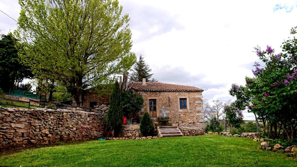 a stone house with a stone wall and a yard at Casa Rural la Insula in Santa María de la Alameda