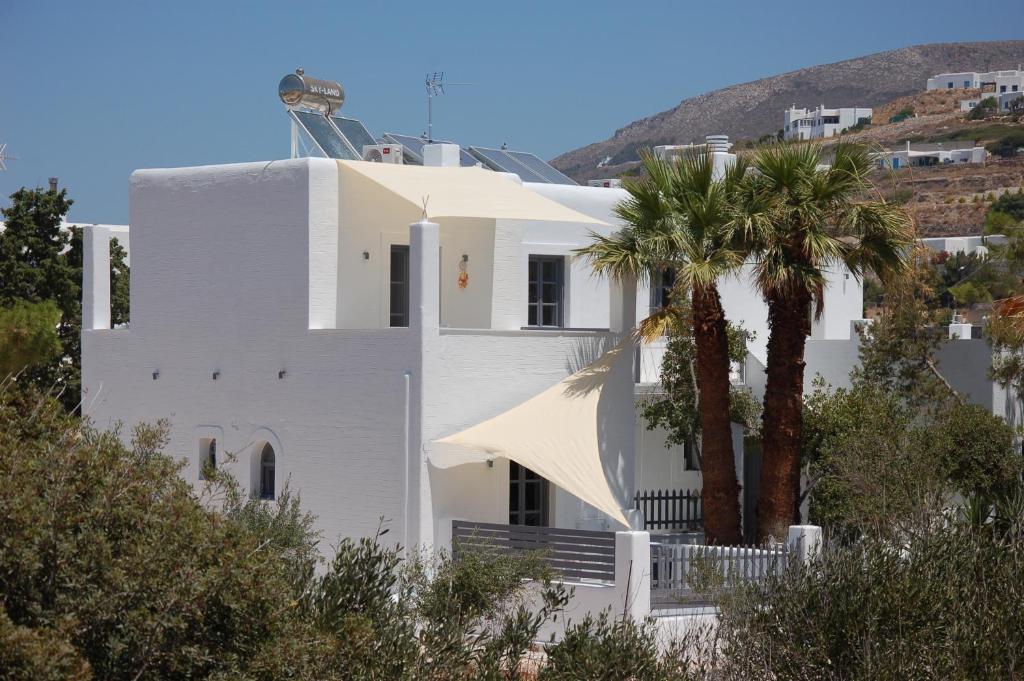 una casa bianca con una palma di fronte di Rodi Apartments a Paroikia