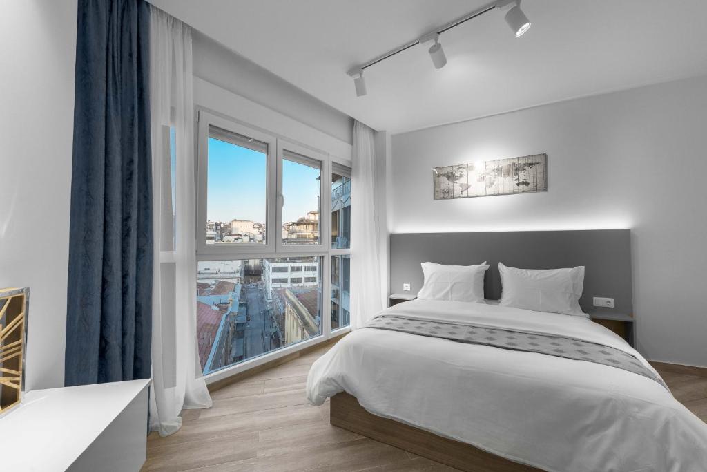 um quarto com uma cama grande e uma janela grande em Hermes Suites, Ermou ST, Nilie Hospitality MGMT em Tessalónica