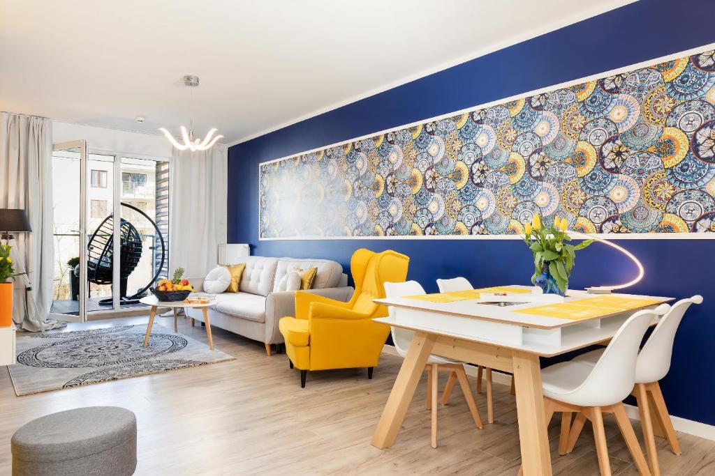a living room with blue walls and a table and yellow chairs at Apartment Aqua Sol Polanki Park Kolberg Schwimmbad, Parkplatz, sonnige Tarasse in Kołobrzeg