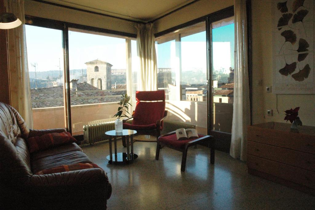 ein Wohnzimmer mit einem Sofa und Stühlen sowie großen Fenstern in der Unterkunft Casa i Colla in Gironella