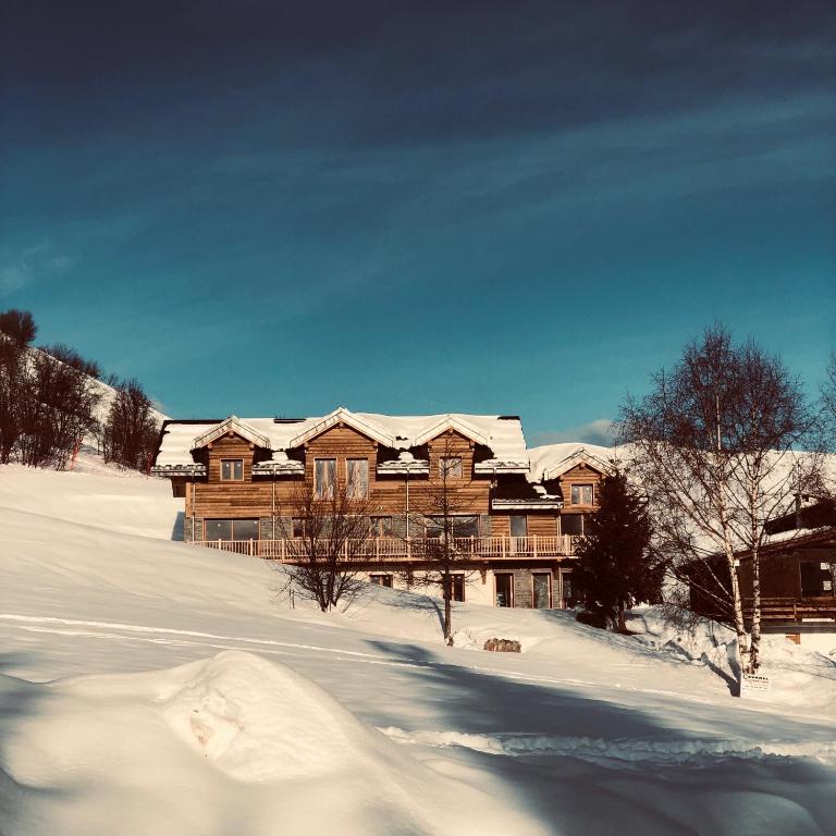une grande maison en bois avec de la neige sur son toit dans l'établissement SKI LODGE, à La Toussuire
