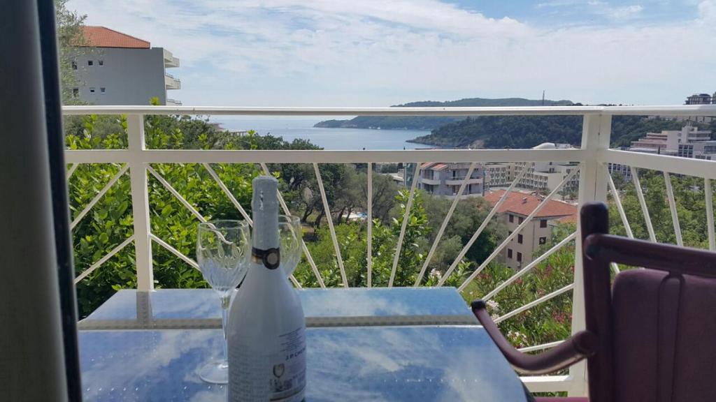 Una botella de vino sentada en una mesa en un balcón en Apartments Nikčević, en Budva