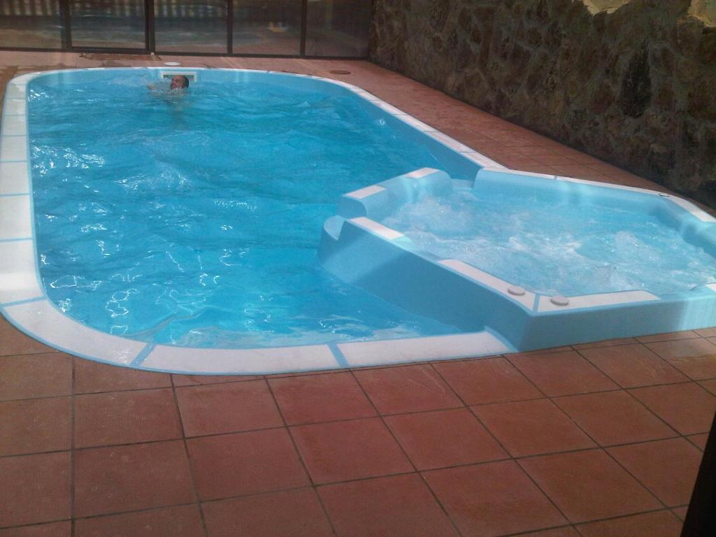 uma grande piscina azul com uma pessoa nela em casa rio alberche y el cortijo de gredos em Navaluenga