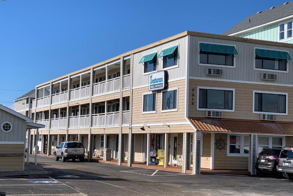 a large building with cars parked in front of it at Sea Horse Inn and Cottages in Nags Head