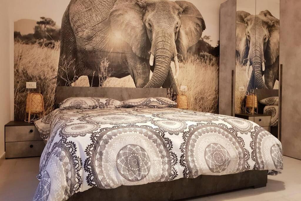 1 dormitorio con 1 cama con una pintura de elefante en la pared en Domus Flavia, en Pozzuoli