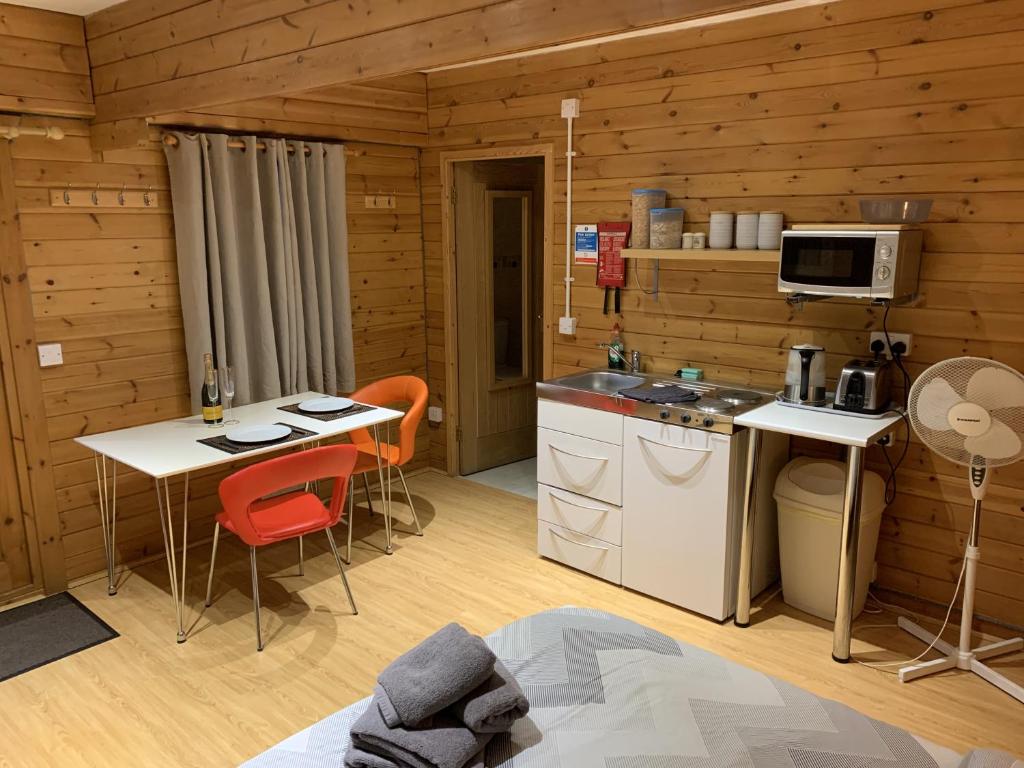 a kitchen in a wooden cabin with a table and chairs at Southernwood - Garden Lodge 4 in Didcot