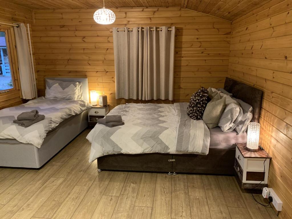 a bedroom with two beds in a wooden cabin at Southernwood - Garden Lodge 8 in Didcot