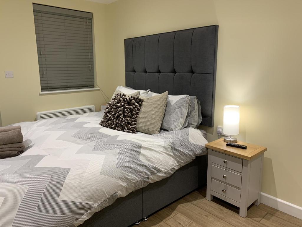 a bedroom with a large bed with a black headboard at Southernwood - Garden Lodge 10 in Didcot