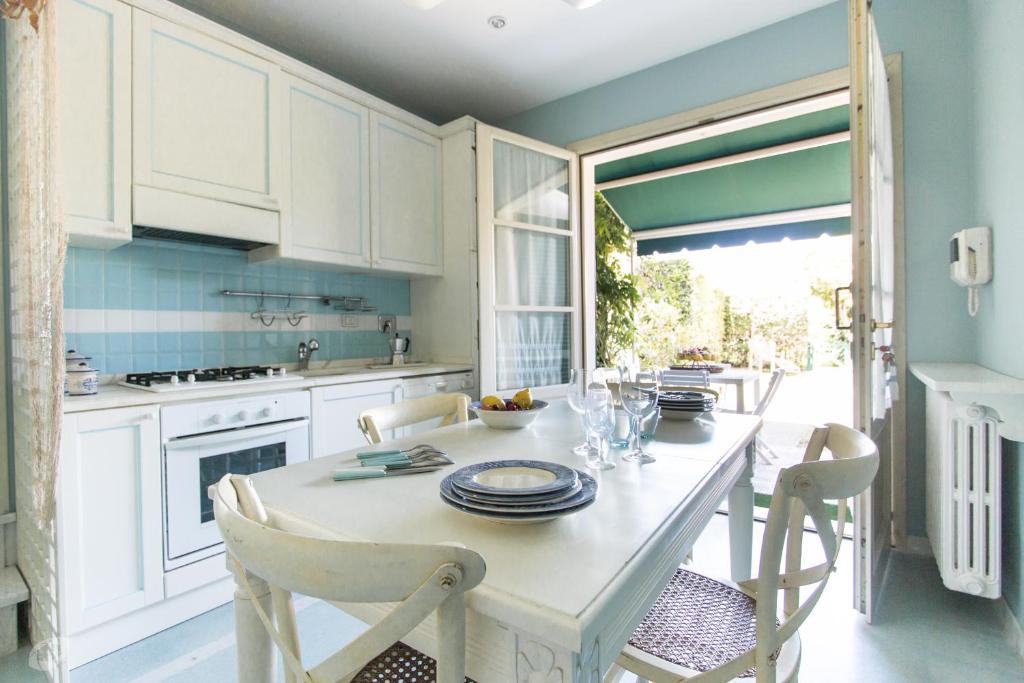 una cucina con armadi bianchi e tavolo con sedie di Villino Azzurro Mare a Marina di Pietrasanta