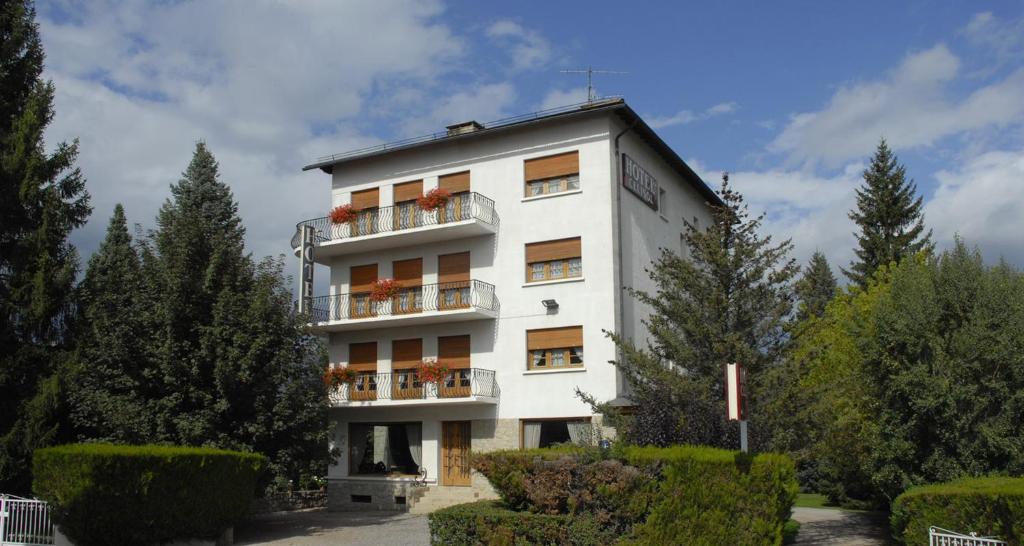 ein weißes Gebäude mit einem Balkon und Bäumen in der Unterkunft Hotel Celisol Cerdagne in Bourg-Madame