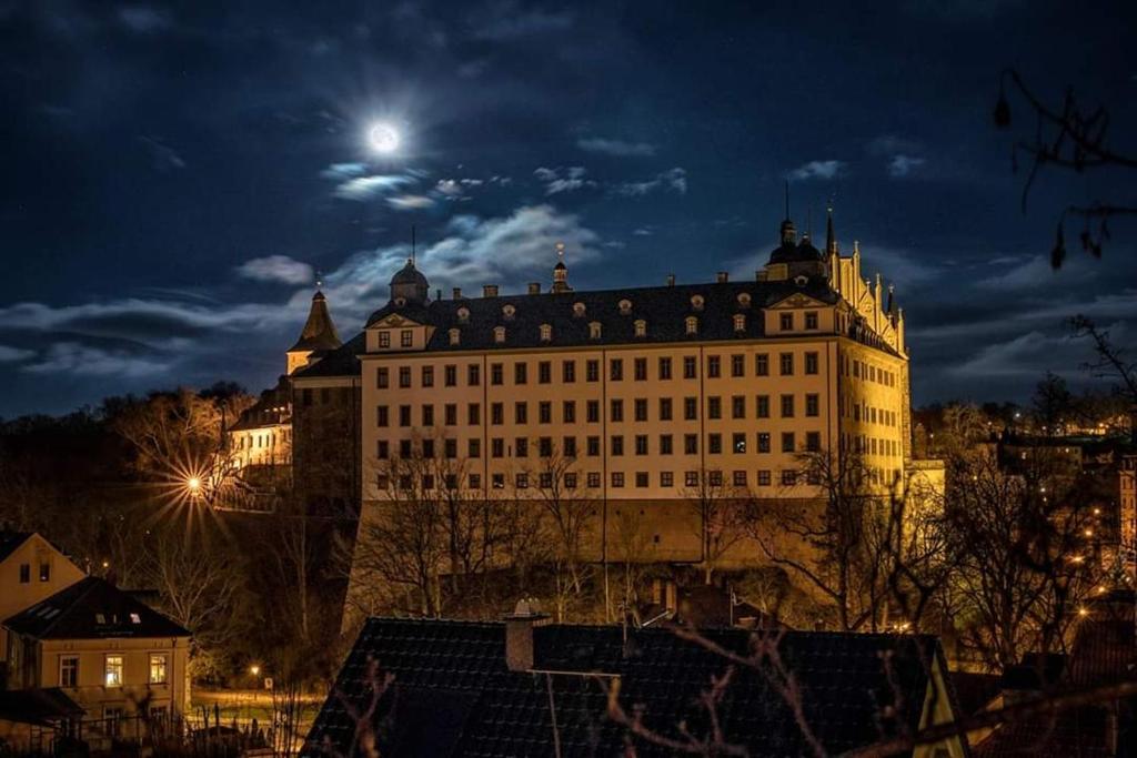 Pension Altenburg City في التنبورغ: مبنى كبير في الليل مع القمر في السماء