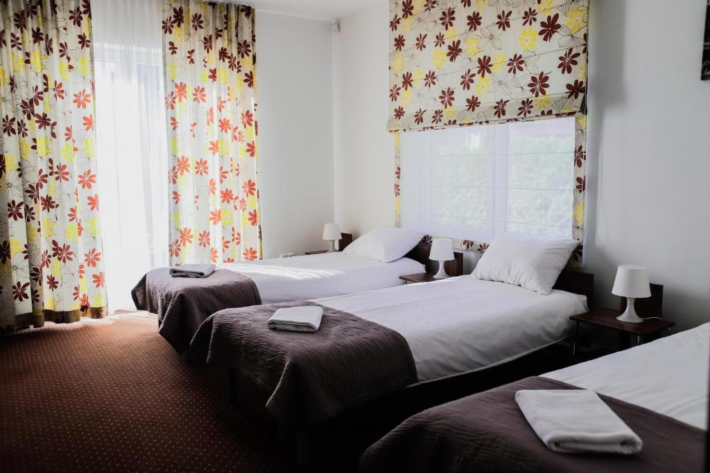 Zimmer mit 2 Betten und einem Fenster mit Vorhängen in der Unterkunft Kalinowy Sen in Warschau