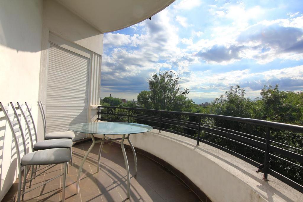a balcony with a glass table and chairs on it at Park View Bucharest in Bucharest